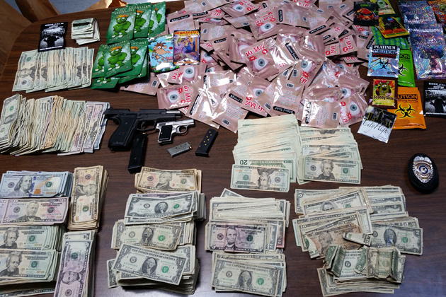 Bloomington Police display the synthetic drugs, weapons and cash seized in a raid on a Clinton Street convenience store last week. (Bloomington Police photo)